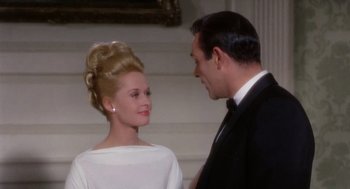 Movie still from “Marnie” (1964), directed by Alfred Hitchcock – A man and a woman standing next to each other in front of a staircase; Medium shot, Low angle