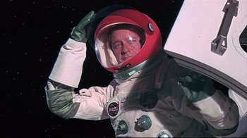 Movie still from “Marooned” (1969), directed by John Sturges – A man in a spacesuit and a red helmet; Medium shot, Overhead angle