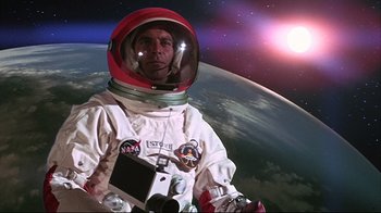 Movie still from “Marooned” (1969), directed by John Sturges – A man in a spacesuit and helmet in front of the earth; Medium shot, Overhead angle