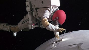 Movie still from “Marooned” (1969), directed by John Sturges – An astronaut in a spacesuit and a red helmet is on a space station; Wide shot, Overhead angle