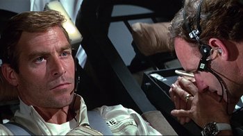 Movie still from “Marooned” (1969), directed by John Sturges – A man and a woman are sitting next to each other in a car; Close Up shot, Over the shoulder angle