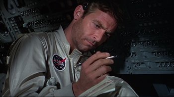 Movie still from “Marooned” (1969), directed by John Sturges – A man in a space suit looking at a cell phone; Close Up shot, Low angle