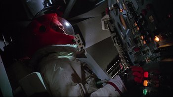 Movie still from “Marooned” (1969), directed by John Sturges – A person in a spacesuit and helmet in a room; Medium shot, Low angle