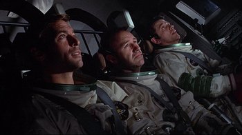 Movie still from “Marooned” (1969), directed by John Sturges – A group of three men sitting next to each other; Medium shot, Low angle