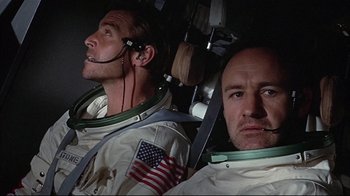 Movie still from “Marooned” (1969), directed by John Sturges – Two men in space suits are sitting next to each other; Close Up shot, Low angle