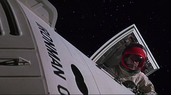 Movie still from “Marooned” (1969), directed by John Sturges – A man in a space suit sitting inside of an airplane; Medium shot, Overhead angle