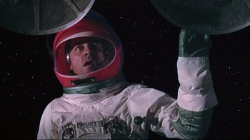 Movie still from “Marooned” (1969), directed by John Sturges – A man in a spacesuit and a red helmet; Medium shot, Overhead angle