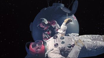 Movie still from “Marooned” (1969), directed by John Sturges – A man in a spacesuit is hanging upside down; Wide shot, Overhead angle