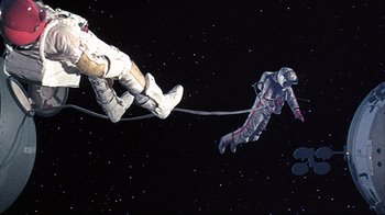 Movie still from “Marooned” (1969), directed by John Sturges – An image of a man in a spacesuit hanging from a rope; Wide shot, Overhead angle