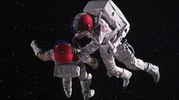 Movie still from “Marooned” (1969), directed by John Sturges – Two people in spacesuits are in the stars; Wide shot, Overhead angle