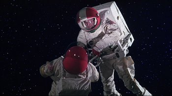 Movie still from “Marooned” (1969), directed by John Sturges – Two people in spacesuits are standing in the stars; Medium shot, Low angle