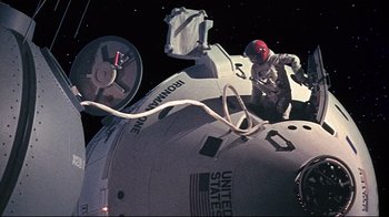 Movie still from “Marooned” (1969), directed by John Sturges – A man in a spacesuit standing on top of a space ship; Wide shot, Overhead angle