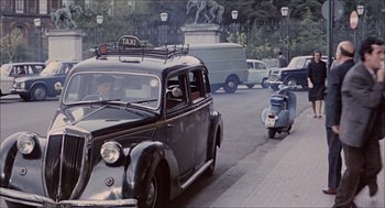 Movie still from “Marriage Italian Style” (1964), directed by Vittorio De Sica – An old fashioned car driving down a street; Wide shot, High angle