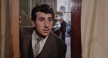Movie still from “Marriage Italian Style” (1964), directed by Vittorio De Sica – A man in a suit standing in front of a bar; Medium shot, Low angle