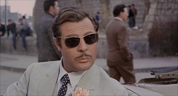 Movie still from “Marriage Italian Style” (1964), directed by Vittorio De Sica – A person wearing a suit and sunglasses; Close Up shot, Over the shoulder angle
