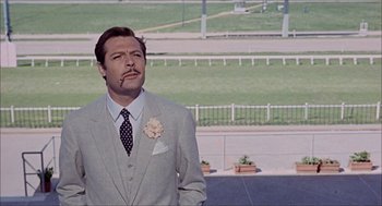 Movie still from “Marriage Italian Style” (1964), directed by Vittorio De Sica – A man in a suit and tie standing in a parking lot; Medium shot, Low angle