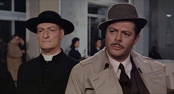 Movie still from “Marriage Italian Style” (1964), directed by Vittorio De Sica – Two men wearing hats and a trench coat; Close Up shot, Low angle