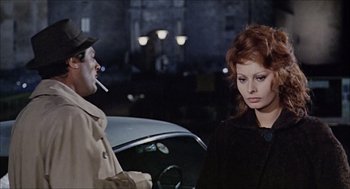 Movie still from “Marriage Italian Style” (1964), directed by Vittorio De Sica – A man and a woman standing next to each other in front of a car; Medium shot, Over the shoulder angle