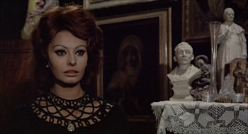 Movie still from “Marriage Italian Style” (1964), directed by Vittorio De Sica – A person wearing a necklace near a statue; Medium shot, Over the shoulder angle