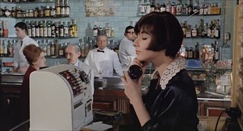 Movie still from “Marriage Italian Style” (1964), directed by Vittorio De Sica – A woman talking on a phone in front of a bar; Medium shot, High angle