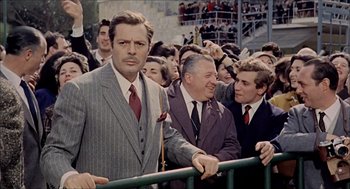 Movie still from “Marriage Italian Style” (1964), directed by Vittorio De Sica – A group of men standing next to each other in front of a crowd; Medium shot, Over the shoulder angle
