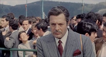 Movie still from “Marriage Italian Style” (1964), directed by Vittorio De Sica – A man in a suit and tie in a crowd of people; Close Up shot, Over the shoulder angle