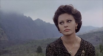 Movie still from “Marriage Italian Style” (1964), directed by Vittorio De Sica – A woman in a black shirt is standing in front of a mountain range; Close Up shot, Over the shoulder angle