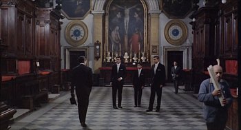 Movie still from “Marriage Italian Style” (1964), directed by Vittorio De Sica – A group of men standing in front of a painting; Wide shot, High angle