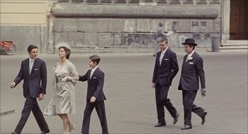 Movie still from “Marriage Italian Style” (1964), directed by Vittorio De Sica – A group of men and a woman walking down a street; Wide shot, High angle