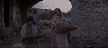 Movie still from “Mary Magdalene” (2018), directed by Garth Davis – A woman holding a basket while standing next to a man; Medium shot, Over the shoulder angle
