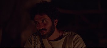 Movie still from “Mary Magdalene” (2018), directed by Garth Davis – A man with curly hair and a beard is sitting in a dark room; Close Up shot, Over the shoulder angle