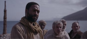 Movie still from “Mary Magdalene” (2018), directed by Garth Davis – A group of men standing next to each other on a beach; Medium shot, Over the shoulder angle