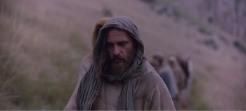 Movie still from “Mary Magdalene” (2018), directed by Garth Davis – A man with long hair and a beard is walking in a field; Close Up shot, Low angle