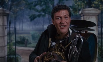 Movie still from “Mary Poppins” (1964), directed by Robert Stevenson – A man smiles while holding a guitar; Medium shot, Low angle