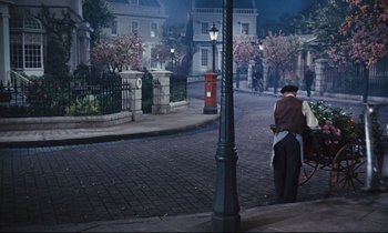 Movie still from “Mary Poppins” (1964), directed by Robert Stevenson – A man riding a bike down a street at night; Wide shot, High angle