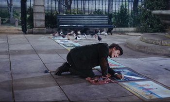 Movie still from “Mary Poppins” (1964), directed by Robert Stevenson – A person sitting on the ground drawing on the ground; Wide shot, High angle