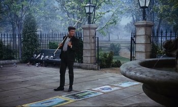 Movie still from “Mary Poppins” (1964), directed by Robert Stevenson – A man in a suit and tie holding an umbrella; Wide shot, High angle