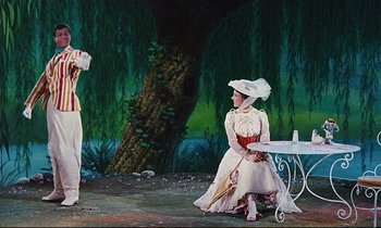Movie still from “Mary Poppins” (1964), directed by Robert Stevenson – A woman in a white dress sitting on the ground next to a table; Wide shot, Low angle