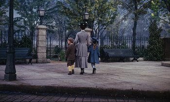 Movie still from “Mary Poppins” (1964), directed by Robert Stevenson – A woman and two children walking down a sidewalk; Wide shot, Low angle