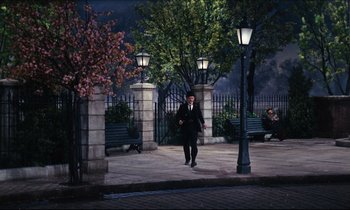 Movie still from “Mary Poppins” (1964), directed by Robert Stevenson – A man in a black suit walking on a sidewalk; Wide shot, High angle