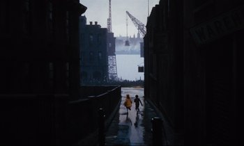 Movie still from “Mary Poppins” (1964), directed by Robert Stevenson – Two children are running down the street in the rain; Extreme Wide shot, High angle
