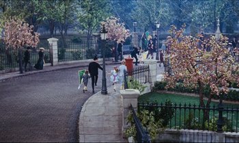 Movie still from “Mary Poppins” (1964), directed by Robert Stevenson – A group of people walking down a sidewalk near trees; Extreme Wide shot, High angle