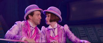 Movie still from “Mary Poppins Returns” (2018), directed by Rob Marshall – A man and a woman wearing purple hats; Medium shot, Over the shoulder angle