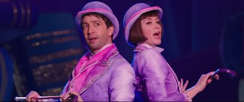 Movie still from “Mary Poppins Returns” (2018), directed by Rob Marshall – A man and a woman dressed in purple and pink; Medium shot, Low angle