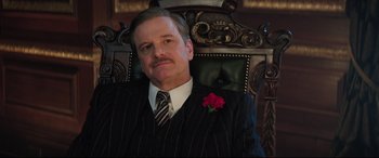 Movie still from “Mary Poppins Returns” (2018), directed by Rob Marshall – A man in a suit and tie sitting in a chair; Medium shot, Low angle