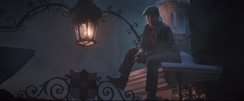 Movie still from “Mary Poppins Returns” (2018), directed by Rob Marshall – A man sitting next to a street light; Wide shot, Low angle