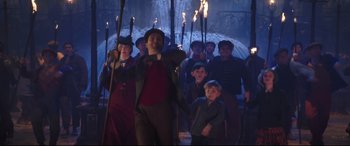 Movie still from “Mary Poppins Returns” (2018), directed by Rob Marshall – A group of people holding torches in the dark; Wide shot, High angle