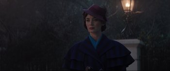 Movie still from “Mary Poppins Returns” (2018), directed by Rob Marshall – A woman wearing a purple hat standing in front of trees; Medium shot, Low angle
