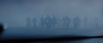 Movie still from “Mary Poppins Returns” (2018), directed by Rob Marshall – A large group of people riding bikes in the fog; Extreme Wide shot, Low angle