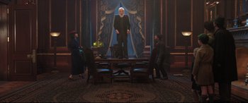 Movie still from “Mary Poppins Returns” (2018), directed by Rob Marshall – A group of people standing around a table; Wide shot, Low angle